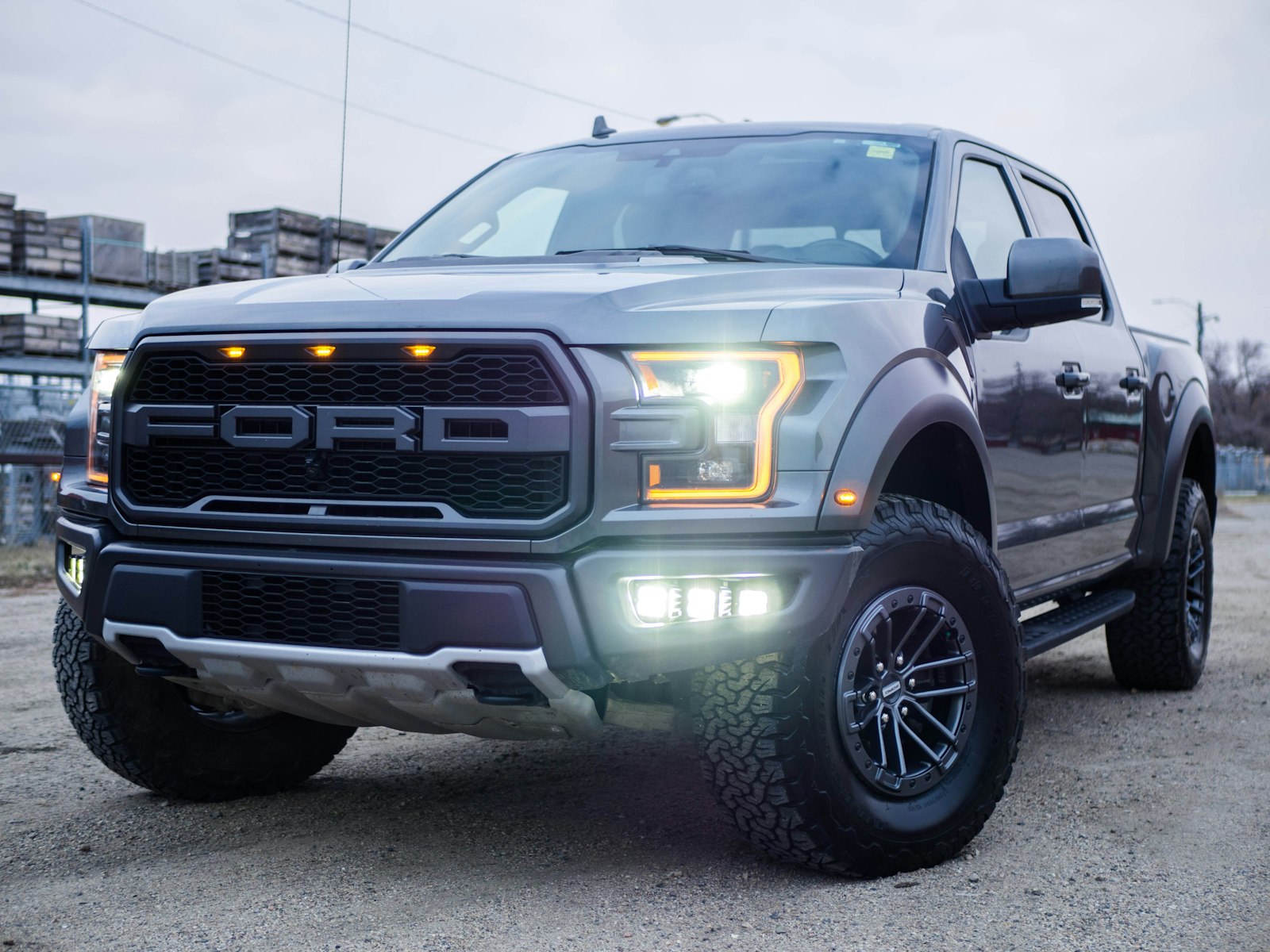 A full-size Ford pickup truck with its lights on, parked outdoors.